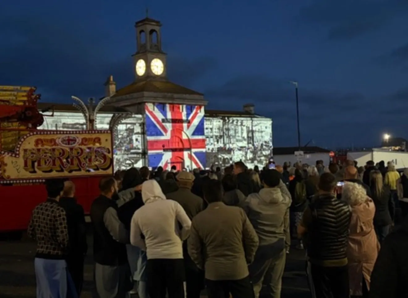 Outdoor crowd watching projections on a town building at night