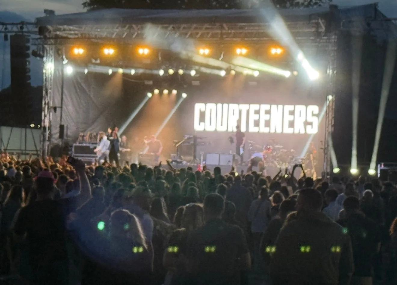 Crowd watching a brightly lit outdoor stage at night